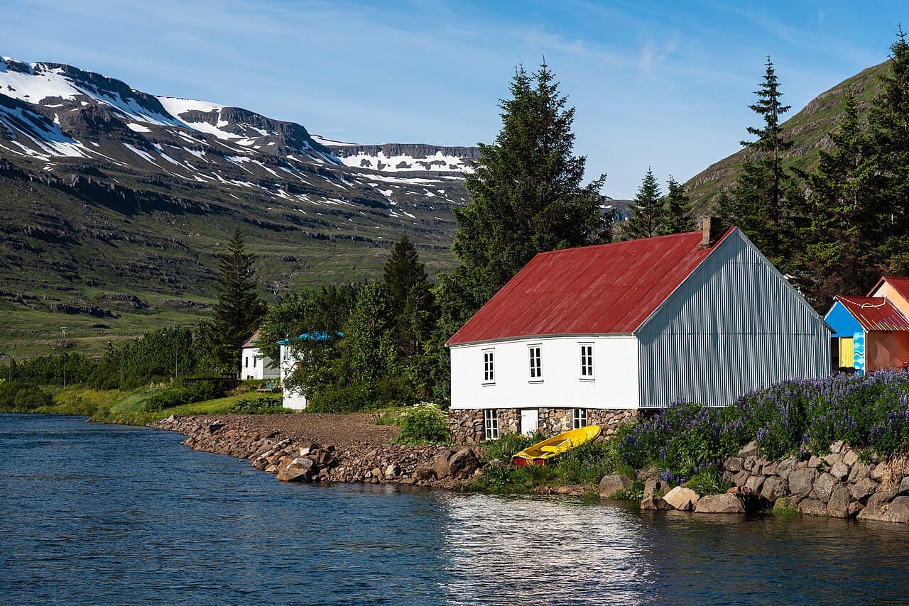 Red-roofed houses along the fjord at Seyðisfjörður in East Iceland, snow-streaked mountains behind