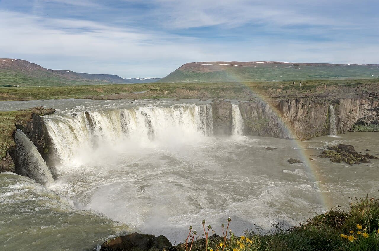 Goðafoss waterfall in North Iceland with a rainbow arcing over the cascade in summer