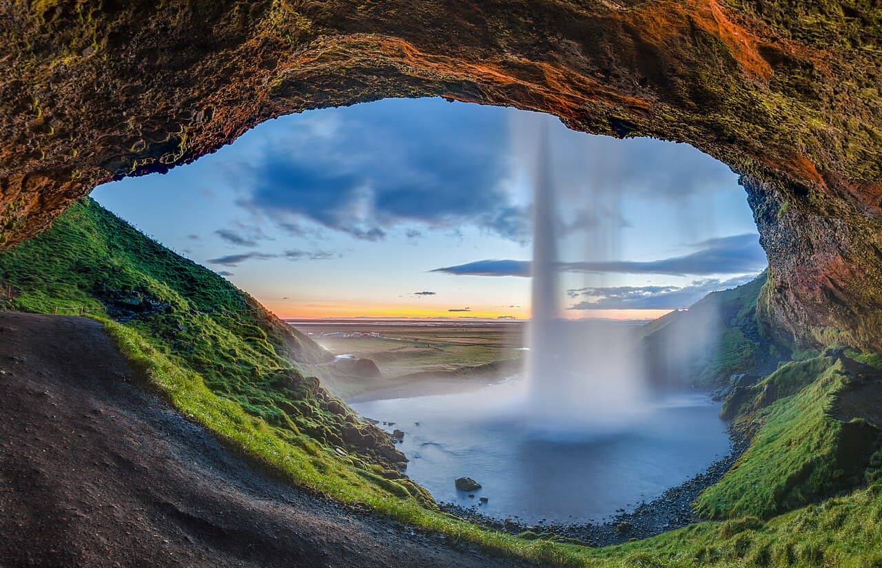 Seljalandsfoss waterfall in South Iceland seen from the cave path behind the falls at sunset