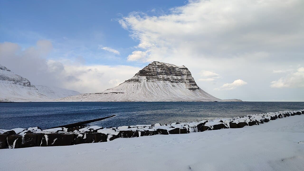 Mount Kirkjufell on the Snæfellsnes Peninsula in West Iceland, snow-capped above a calm fjord in winter